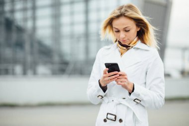 Şehirde akıllı telefon kullanan güzel ve mutlu kız portresi. Telefonunuzun ve kopya alanı ile büyük bir şehirde genç kadın.