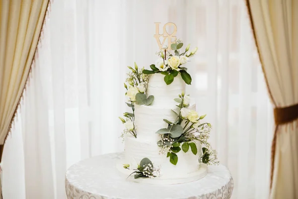White wedding cake with flowers.  The word Love with heart.