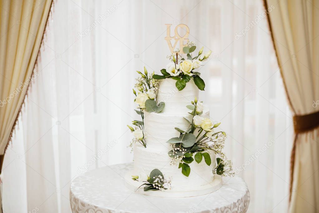  White wedding cake with flowers.  The word Love with heart.