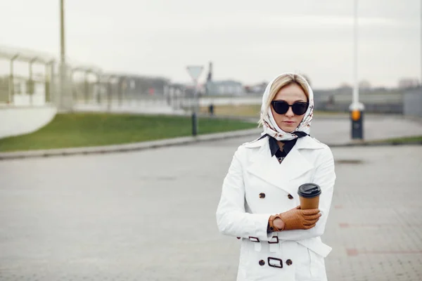 Young stylish pretty woman posing in the city streets and using — Stock Photo, Image