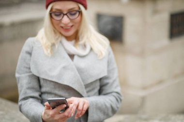 Şehrin sokaklarında yürürken ve modern smartphone kullanarak güzel kadın.