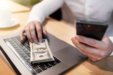 dizüstü bilgisayar ve arka plan üzerinde para olan adam.