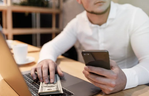 man with laptop and money on background.