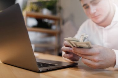 dizüstü bilgisayar ve arka plan üzerinde para olan adam.