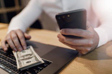 dizüstü bilgisayar ve arka plan üzerinde para olan adam.