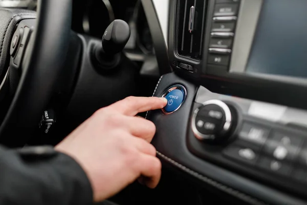 driver pushing car engine start-stop button in modern car.