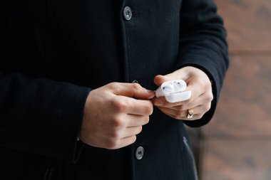 Kablosuz kulaklık sokaklarda gösterilen genç adam. Airpods olan adam.