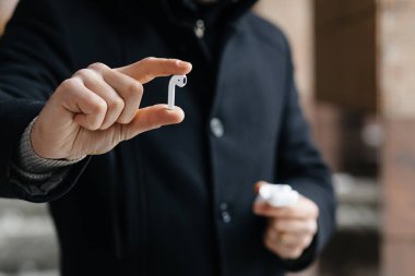 Kablosuz kulaklık sokaklarda gösterilen genç adam. Airpods olan adam.