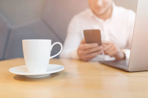 Mans handen met behulp van slimme telefoon en laptop in interieur. — Stockfoto