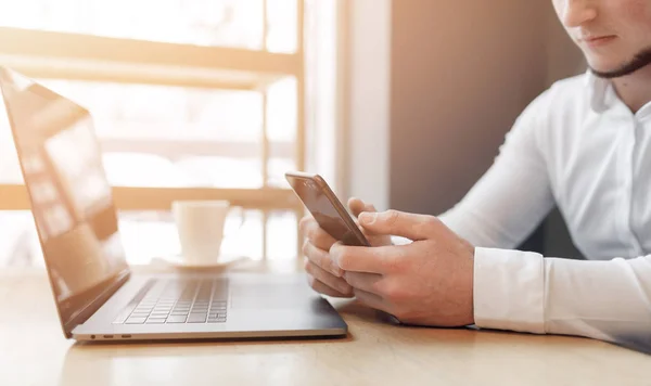 Mans hands using smart phone and laptop in interior. — Stock Photo, Image