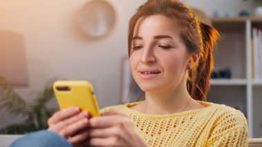 Evde cep telefonunu kullanan güzel bir genç kadının portresi.