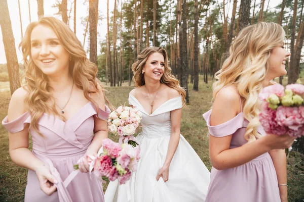 美丽的新娘和她漂亮的伴娘 新娘和伴娘手里拿着花束 — 图库照片
