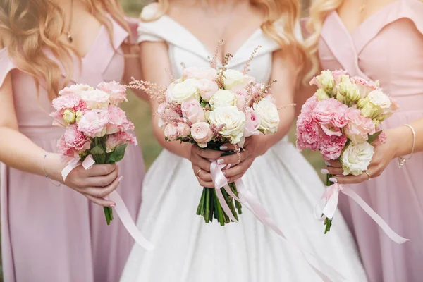 Bridesmaids holding bouquets. Wedding bouquet in hands. Beautiful bride with her pretty bridesmaids.