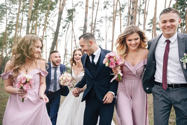 Beautiful couple with the friends. Newlyweds and friends hugging outside. Couple, bridesmaids & groomsmen having fun outdoors