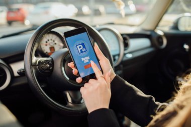 Arabada bir iş kadını. Park için ödemek için Smartphone uygulaması kullanan kız.