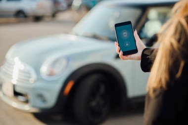 Car yakınındaki bir iş kadını. Arabanın yakınında Smartphone kullanan kadın. Araba sahipleri kavramı için cep telefonu uygulamaları.