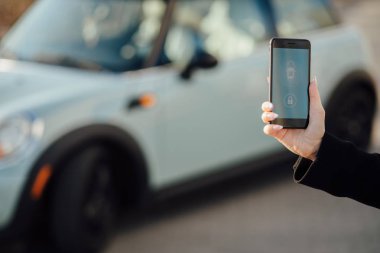Car yakınındaki bir iş kadını. Arabanın yakınında Smartphone kullanan kadın. Araba sahipleri kavramı için cep telefonu uygulamaları.
