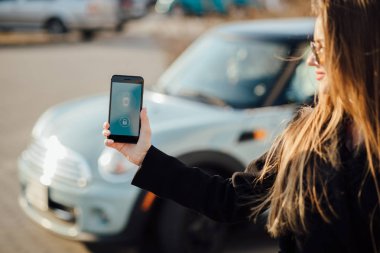 Car yakınındaki bir iş kadını. Arabanın yakınında Smartphone kullanan kadın. Telefon denetiminde araba.