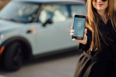 Car yakınındaki bir iş kadını. Arabanın yakınında Smartphone kullanan kadın. Araba sahipleri kavramı için cep telefonu uygulamaları.