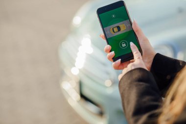 Car yakınındaki bir iş kadını. Arabanın yakınında Smartphone kullanan kadın. Araba sahipleri kavramı için cep telefonu uygulamaları.