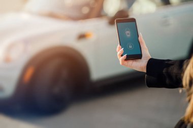 Car yakınındaki bir iş kadını. Arabanın yakınında Smartphone kullanan kadın. Araba sahipleri kavramı için cep telefonu uygulamaları.