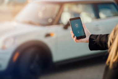 Car yakınındaki bir iş kadını. Arabanın yakınında Smartphone kullanan kadın. Araba sahipleri kavramı için cep telefonu uygulamaları.