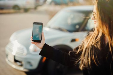 Car yakınındaki bir iş kadını. Arabanın yakınında Smartphone kullanan kadın. Telefon denetiminde araba.