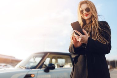 Car yakınındaki Smartphone kullanan kız.