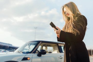 Car yakınındaki Smartphone kullanan kız.