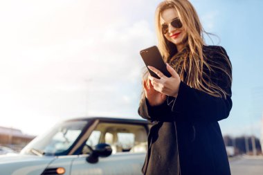 Car yakınındaki Smartphone kullanan kız.