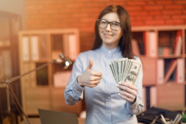 Para banknot tutan neşeli genç kadın. Son derece yüz tutan gözlük işkadını Doları banknot ayrıntılı.