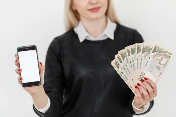 Жінка тримає гроші і використовує смартфон . — стокове фото