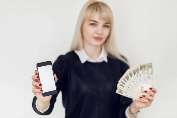 Woman holding money and using smartphone.