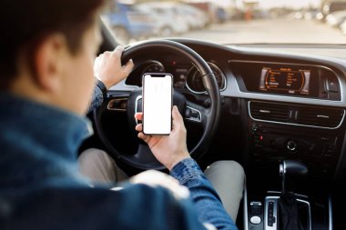 Arabadaki adam. Arabada telefonu olan genç bir iş adamı. Boş ekranlı akıllı telefonu tutan adam .