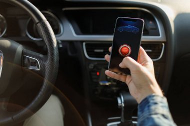 Arabadaki adam. Arabada telefonu olan genç bir iş adamı. Akıllı telefon araç güvenlik başlangıç motoru kontrol eder.