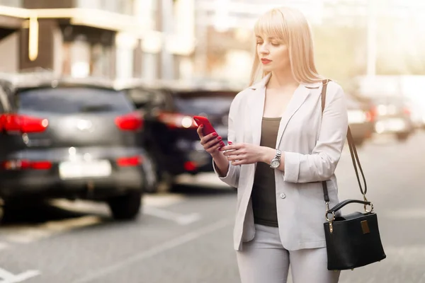Business woman using phone on car background. Girl hands using mobile smart phone.