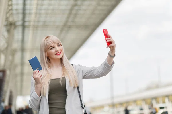 Portrait of business female traveler with at airport. Beautiful sexy blond woman traveler holding passport with ticket and credit card.