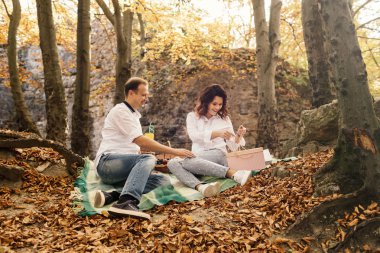 Romantik genç çift sonbahar parkında yürüyor. Parkta birlikte bir aile. Hamile çift.