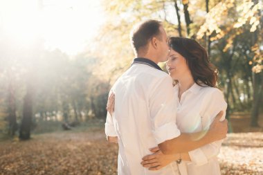 Romantik genç çift sonbahar parkında yürüyor. Parkta birlikte bir aile. Hamile çift.