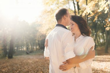 Romantik genç çift sonbahar parkında yürüyor. Parkta birlikte bir aile. Hamile çift.