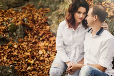 Romantik genç çift sonbahar parkında yürüyor. Parkta birlikte bir aile. Hamile çift.