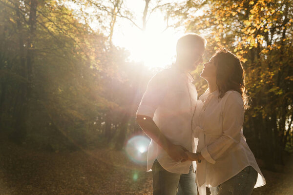Romantic young couple walking in autumn park. Family together in the park. Pregnant couple.