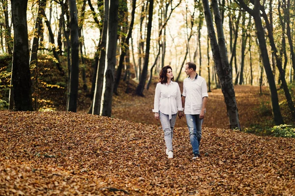 Romantic young couple walking in autumn park. Family together in the park. Pregnant couple.