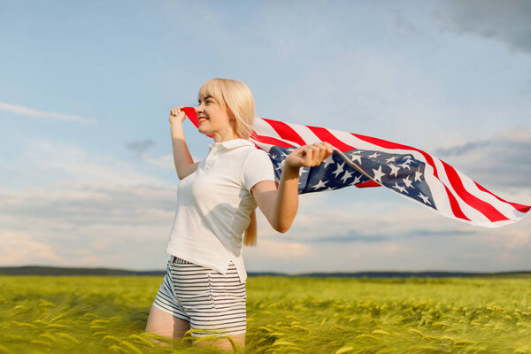 Woman holding American flag in wheat field. Patriots of America. Girl celebrating 4th of july.