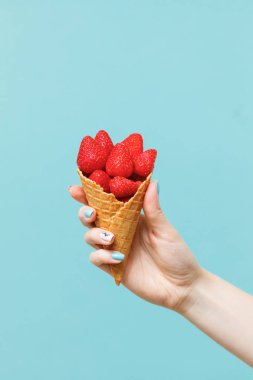 Kadın elinde çilek ile waffle koni. Taze yaz meyveleri.