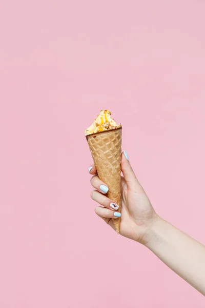 Woman holding Ice Cream in a waffles cone on color background.