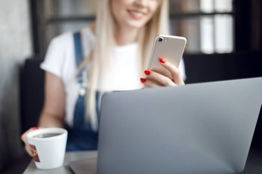 Kafede kahve içen ve cep telefonu kullanan genç kız. Online alışveriş