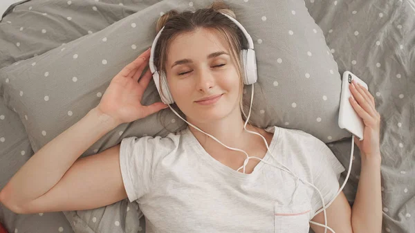 Mulher feliz ou adolescente em fones de ouvido ouvindo música do smartphone — Fotografia de Stock