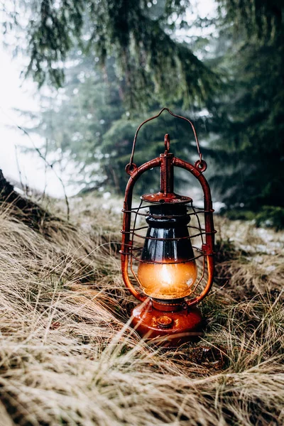 Primer plano de la linterna con una luz en el interior en el suelo cubierta con un heno seco en el bosque de pinos en el día frío brumoso. Afuera. . —  Fotos de Stock