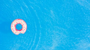 Summer Vacation. Aerial view of big pink donut in the swimming pool. clipart